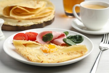 Delicious crepe with egg, ham and parmesan cheese served on white wooden table, closeup