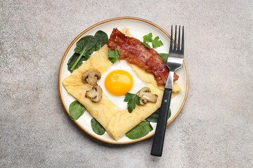 Delicious crepe with egg, bacon and mushrooms served on grey table, top view. Breton galette