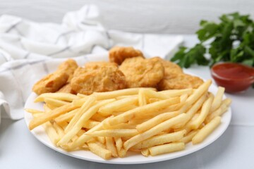 Tasty chicken nuggets and french fries with sauce on white tiled table, closeup