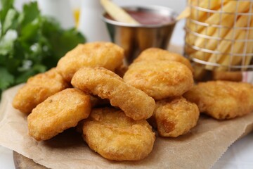Tasty chicken nuggets, potato fries and ketchup on white table, closeup