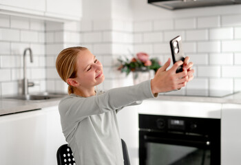 Cute Little Girl Taking A Selfie With Smartphone And Smiling At Home