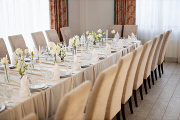 large beautiful banquet table in a restaurant with tablecloth and floral decor
