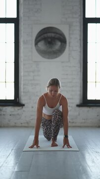 Fit Blonde Woman in Leopard Leggings Performing Advanced Forearm Yoga Pose in Bright Studio