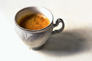White cup of espresso coffee on white.