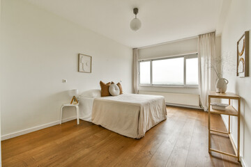 A spacious and airy modern bedroom featuring a comfortable bed, soft decor, and natural light streaming through large windows, creating a serene atmosphere.