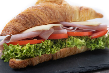 Título Croissant with ham, cheese and vegetables on wooden table.