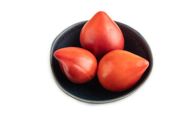 Red Heart shape tomatoes in blue bowl isolated on white. Side view, copy space