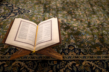 Obraz premium An opened holy book of the Quran on a green carpet at the Prophet Mosque, Masjid Nabawi in the city of Medina, Saudi Arabia