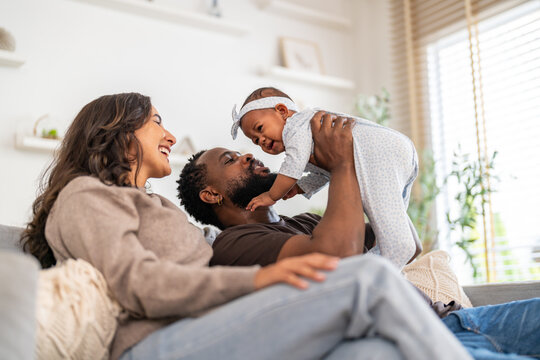 African family happy play at home, loving father holding and playing with baby while mother watches with joy, happy parenting moment full of love, affection, care and connection in cozy family at home