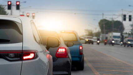 Line of cars stopped at a traffic light during daylight. Cars are in focus  with a blurred background of more vehicles and traffic lights  suggesting a busy intersection.