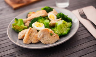 Pieces of fried chicken breast with boiled broccoli and quail eggs on plate for lunch