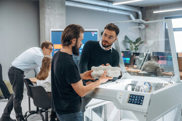Standing. Modern technology. People are in the office by the 3d printer