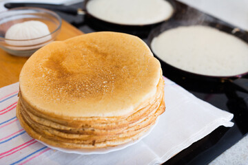 Freshly baked hot cereal pancakes on plate and pans during cooking