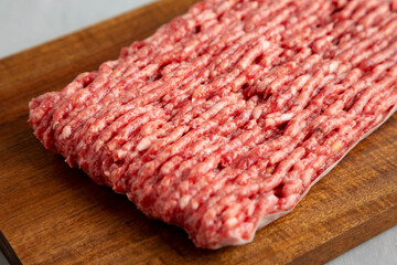Organic Grass Fed Raw Chuck Ground Beef on a Wooden Board, side view.