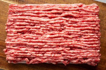 Organic Grass Fed Raw Chuck Ground Beef on a Wooden Board, top view. Close-up.