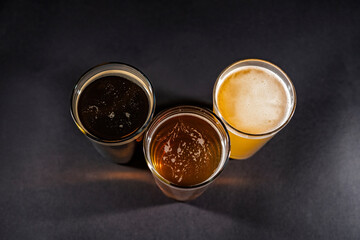 Three glasses of beer in the middle on black chalkboard backgorund