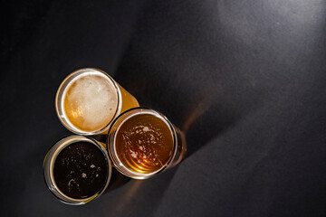 Three glasses of beer in the lower left corner with empty space on the right, top view
