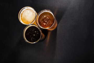 Three glasses of beer in the upper left corner with empty space on the right, top view