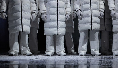 Closeup of men in white puffer coats on stage