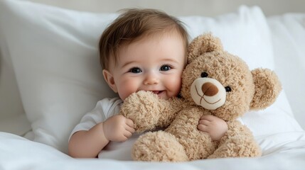 Happy baby cuddling teddy bear in bed
