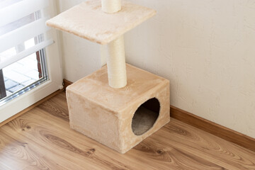A beige cozy cat tree house without a cat standing in living room at home