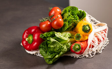 Close up of fresh seasonal vegetables in an eco net shopper bag on grey kitchen table