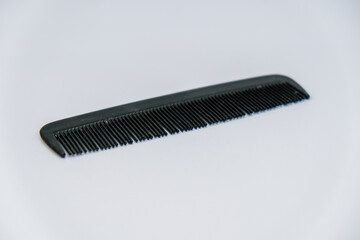 Small Black plastic comb up on white background. Comb for the head, pocket comb