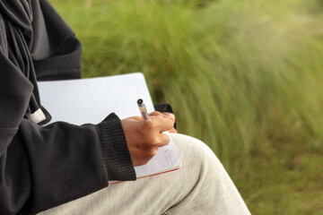 Close Up of Woman Writing in Notebook Outdoors