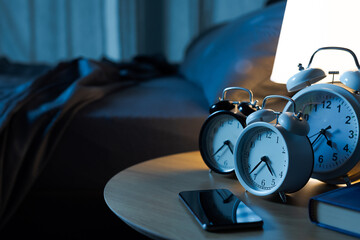 Many alarm clocks on the bedside table