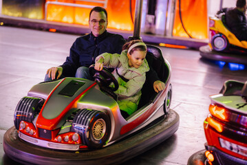 Father and daughter enjoying bumper cars ride at amusement park