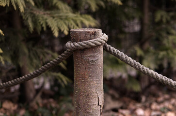 A rope wrapped around a wooden stake. Barrier made of natural material. Fence made of natural...