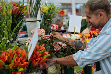 Florist arranging roses and lilies in flower shop