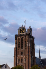 A majestic Gothic church under a dramatic cloudy sky. The intricate brickwork, towering windows, and clock tower reflect its historic architecture and timeless grandeur.