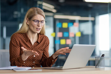 Anxious and nervous woman working with laptop inside office at workplace. Businesswoman got error...