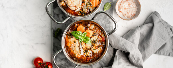 Traditional French bouillabaisse soup with fish fillets and seafood in tomato sauce. Top view.