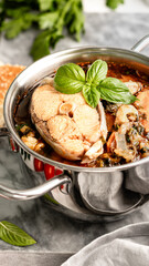 Traditional French bouillabaisse soup with fish fillets and seafood in tomato sauce.