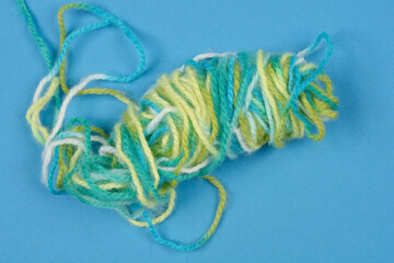A top-down shot of a loosely coiled bundle of multi-colored yarn against a blue background
