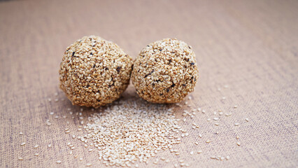 Traditional Indian sweet balls made with sesame seeds, jaggery and coconut, commonly known as Til ke laddu or sesame ladoos. Shot on brown background