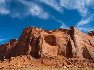 Fototapeta premium Red sandstone cliffs under a vibrant blue sky with scattered clouds in Monument Valley.