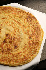 Close-up of a large, round flatbread on a white cloth, top view. Freshly baked flatbread with a golden crust