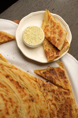 Close-up of flatbread served with a creamy dip and a glass of tea on a white cloth