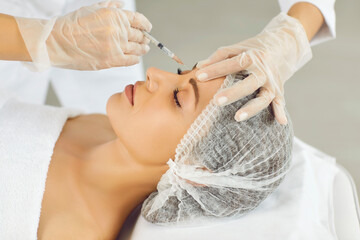 Hands of cosmetologist in gloves making rejuvenation anti wrinkle injection in beautiful woman face...