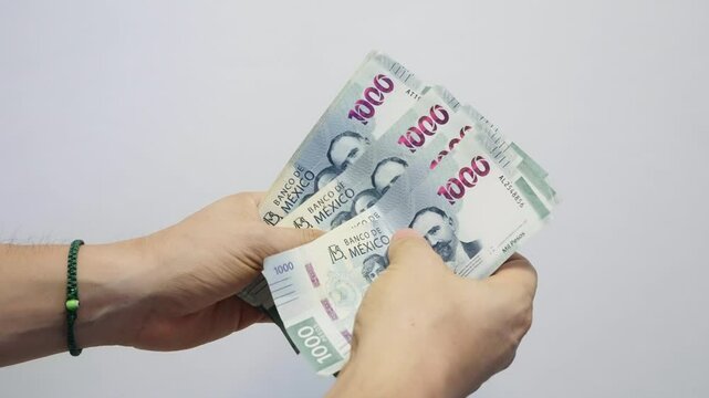 Man counting several five hundred mexican pesos banknotes on a white background