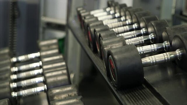 Focus pull of dumbbell weights lined up on a weight rack