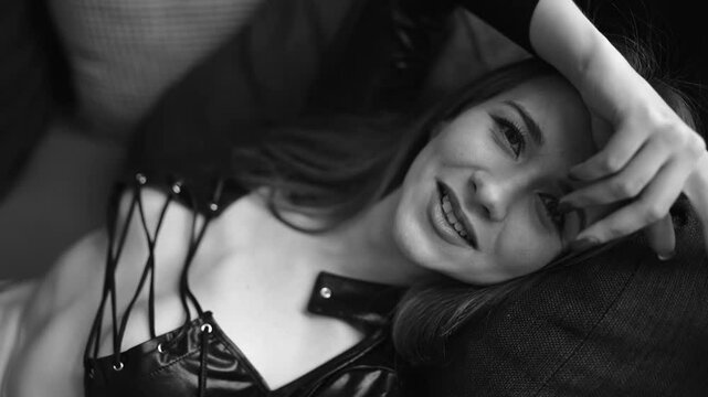  Young woman wearing in the sexual leather clothes on the sofa