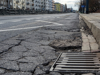 Damaged Asphalt Road Surface with Cracks and Drain Highlighted