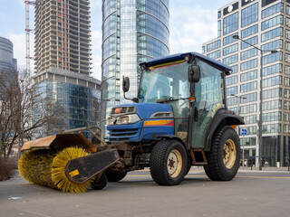 Street Sweeper Tractor with Brush Attachment in Urban Environment
