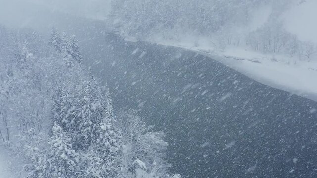 スーパースロー映像：ドローンで空撮した、大雪の日の川の上の風景