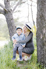 Pregnant mother and her little son walking and hugging in the forest and funny spending time together.