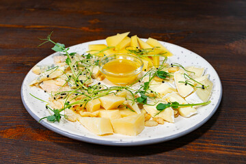 Assorted cheese platter with honey and fresh sprouts for sharing